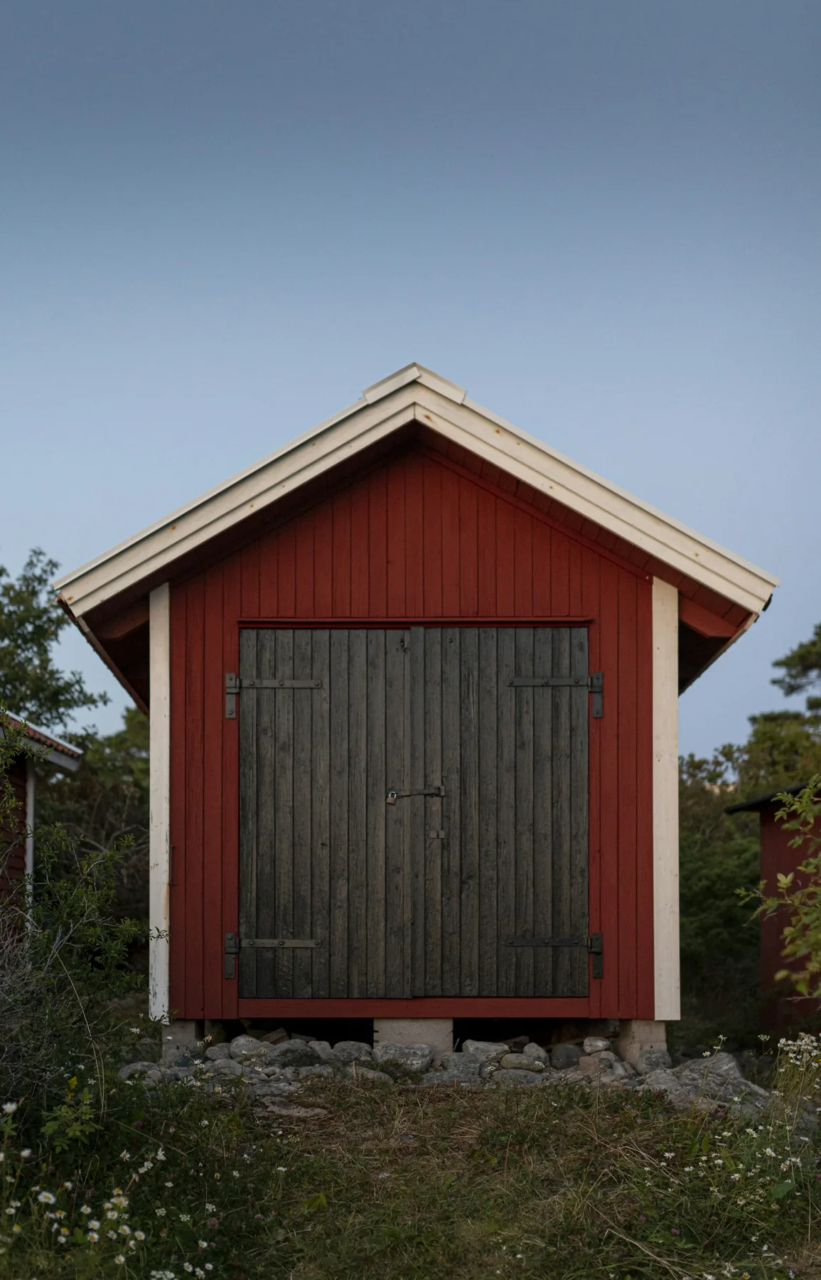 Rödmålad komplementbyggnad med stor port